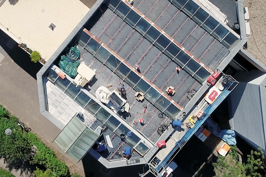 Aufnahme mit der Drohne, zeigt ein Flachdach von oben, welches gerade bearbeitet wird.