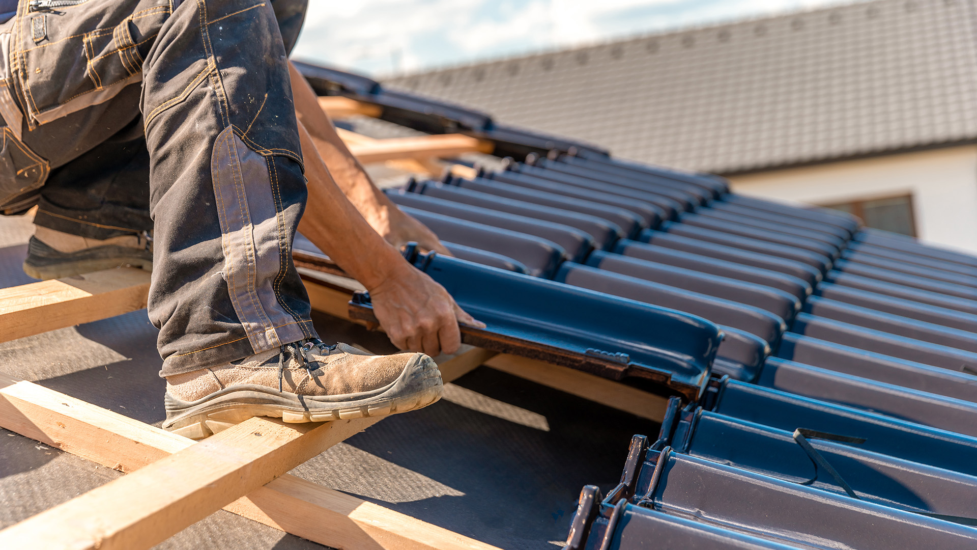Professioneller Dachdecker montiert neue Dachziegel auf einem Steildach – Dachsanierung und Neueindeckung vom Fachbetrieb, sowei Dachreparatur